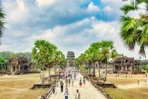 Tourists explore the iconic Angkor Wat in Siem Reap, Cambodia, under a bright sky.